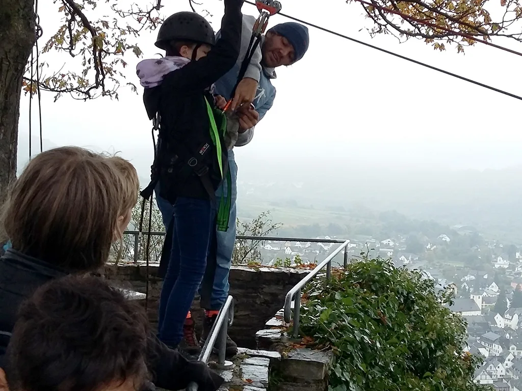 Jugendliche werden am Start der Seilrutsche gesichert.